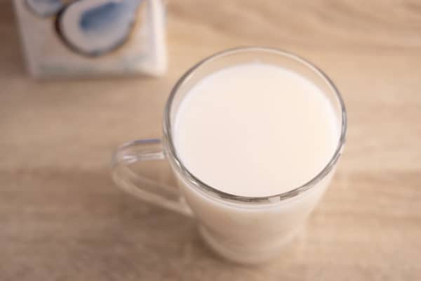 Glass of coconut milk and carton