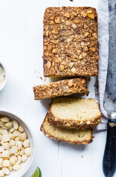 Nuts topped loaf of bread and a bowl of macadamia nuts