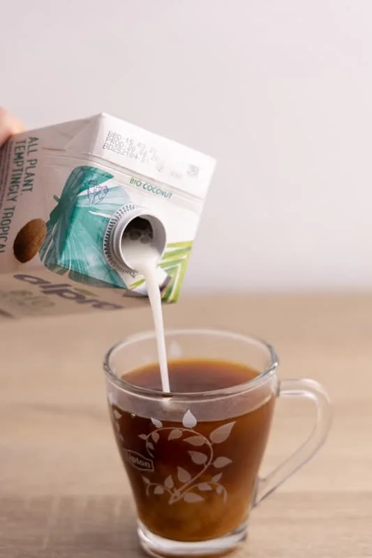 Pouring coconut milk to coffee