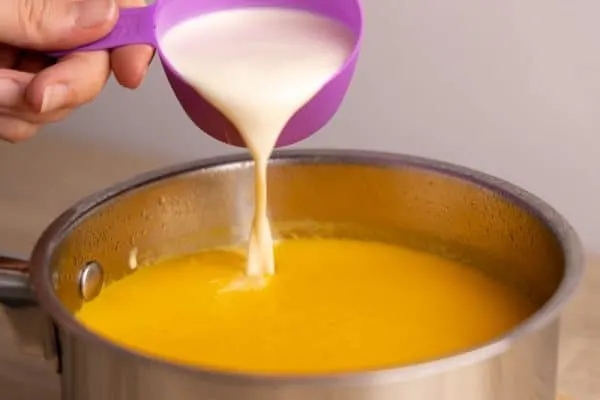 Pouring evaporated milk to soup