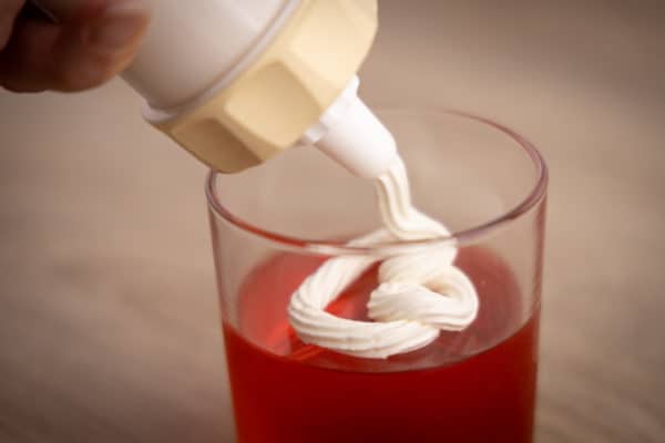 Pouring whipped cream on jello