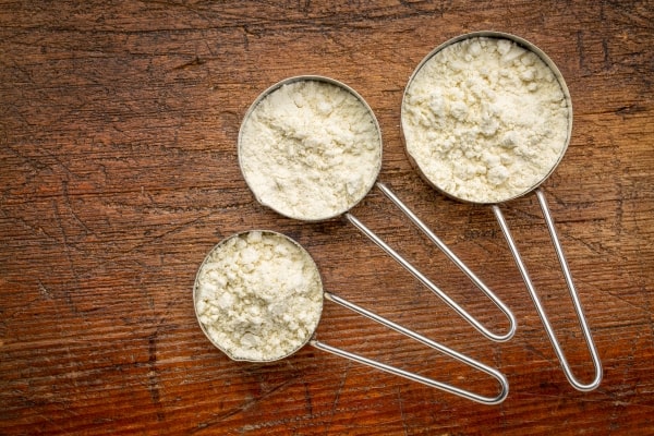 Three measuring metal scoops of whey protein powder