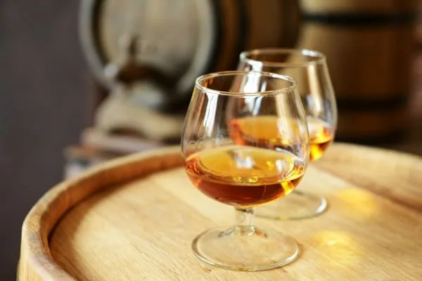Two glasses of brandy in a cellar with old barrels