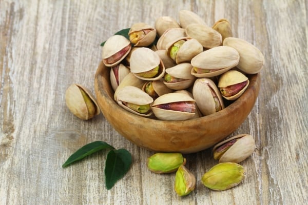 Unshelled pistachios in a wooden bowl